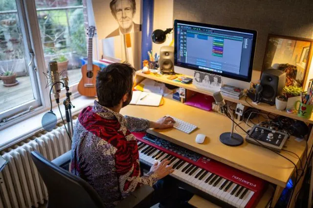 Musicien composant une chanson dans son home studio avec un ordinateur et un clavier MIDI